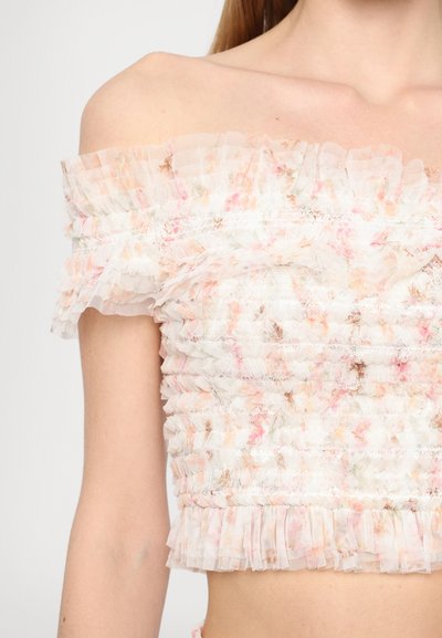 Crop top cu umeri descoperiți, realizat dintr-un material ușor cu un model floral, având margini volanate și un design smocked în culori pastel.