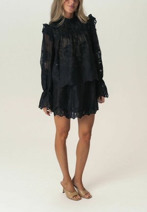 Schwarzes, geschichtetes Blusen- und Rockset aus transparenter Blumenstoff, mit Rüschenkanten und langen Ärmeln. Glatte, leichte Textur.