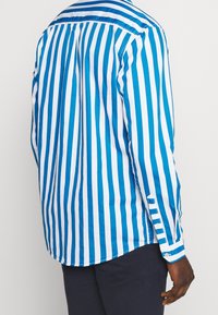 Blauw-wit gestreepte blouse met lange mouwen en een button-down kraag, met een gebogen zoom en knoopsluiting bij de manchetten. Zacht katoenen stof.