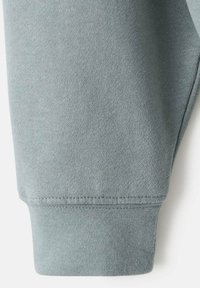 Polsino di felpa blu chiaro melangiato, caratterizzato da una morbida texture tessile, bordo a coste e dettagli delle cuciture lisci.