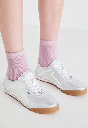 Silberne Sportschuhe mit weißen Akzenten und Gummisohlen, kombiniert mit gerippten rosa Socken, die ein niedriges Profildesign zeigen.