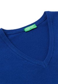 V-Ausschnitt Pullover in leuchtendem Blau, hergestellt aus weichem Strickmaterial. Verfügt über einen gerippten Ausschnitt und ein grünes Etikett mit "United Colors of Benetton."