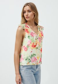Ärmelloses Top mit floralem Muster in hellgelb mit rosa und grünen Motiven, versehen mit einem rüschierten V-Ausschnitt und einer Knopfleiste vorne.