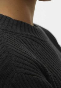 Maglione aderente nero lavorato a maglia con una texture a coste e un collo rotondo. Il design presenta linee verticali e una vestibilità attillata.