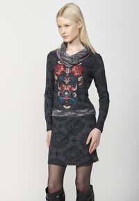 Schwarzes gemustertes Kleid mit langen Ärmeln, Rollkragen und gestickten floralem Akzenten in Rot, Blau und Gold. Figurbetontes Design, strukturierter Stoff.