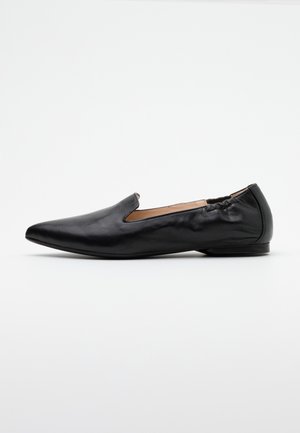 Chaussure plate en cuir noir avec bout pointu, partie arrière élastiquée et talon bas, présentée de profil sur fond blanc uni.