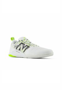 White athletic shoe featuring a mesh upper with green accents, black logo detailing, round toe, and textured rubber outsole.