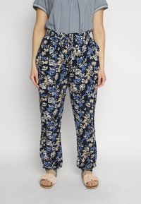 Blomsterprintede bukser i marineblå med lysebeige og blå detaljer. Elastisk talje, to sidelommer og løs pasform. Sammen med lyse sandaler.