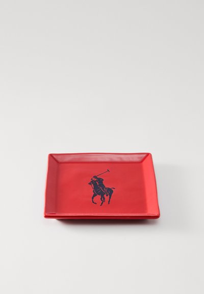 Κόκκινη τετράγωνη πλακέτα από κεραμικό, με σχέδιο σιλουέτας μπλε παίκτη πόλο στο κέντρο. Λεία υφή και ίσιες άκρες.