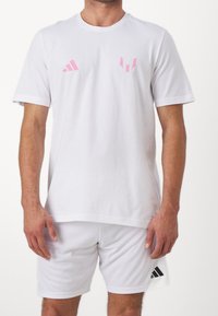 White athletic t-shirt with short sleeves, featuring pink adidas logos on the chest; paired with matching white shorts and black accents.