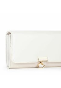Witte patenten leren portemonnee met een gouden sluiting en een decoratieve charme met heldere rhinestones, met een glad en strak exterieur.