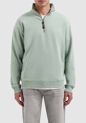 Lichtgroen sweatshirt met een kwart-rits kraag en geribbelde mouwen. Heeft een geborduurd logo en een zachte, gladde stofstructuur.