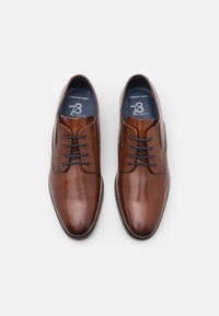 Bruine leren dresschoenen met een gepolijste afwerking, ronde neus en een vetersluiting met vijf oogjes. Bevat "Comfort Wide" branding aan de binnenkant.