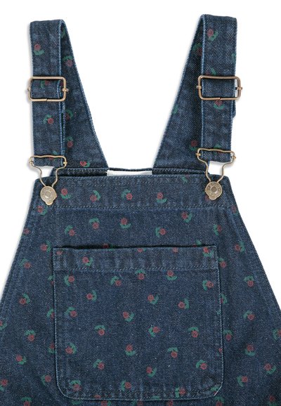 Salopette en denim avec bretelles réglables et fermetures métalliques, avec une poche avant et un petit motif floral rouge et vert.