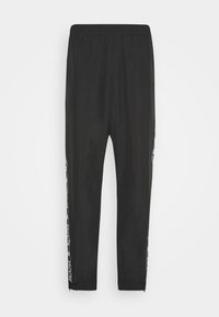 Zwarte sportbroek met elastische tailleband en taps toelopende benen, met witte gestreepte patronen langs de zijkanten en ritsen op de enkels.