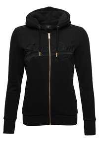 Felpa nera con zip, realizzata in un mix di cotone, dotata di zip dorata, cordini e logo "SuperDry" ricamato sul davanti.