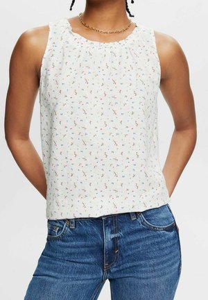 Biały top bez rękawów z marszczonym dekoltem, ozdobiony rozproszonym wzorem kwiatowym w kolorach różowym i niebieskim na fakturowanej tkaninie. W zestawie z dżinsami.