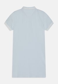 Jasnoniebieska koszulka polo z krótkimi rękawami, z kołnierzykiem oraz prążkowanymi zdobieniami w kolorze białym i jasnoniebieskim na mankietach rękawów. Brak widocznych grafik.