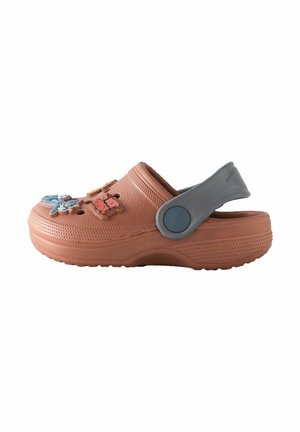 Orange rubber clog with textured surface, featuring decorative charms, a grey adjustable heel strap, and a raised sole for comfort.