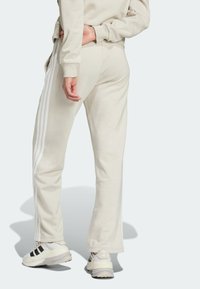 Beiga sweatpants med vita sidostråk, avslappnad passform och en mjuk textur. Matchas med vita och svarta skor för en avslappnad stil.