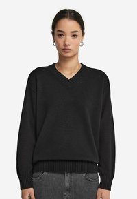 Czarny sweter dzianinowy z dekoltem w kształcie V, prążkowanym dołem i mankietami, o luźnym kroju. Miękka struktura i prosty design, idealny na co dzień.