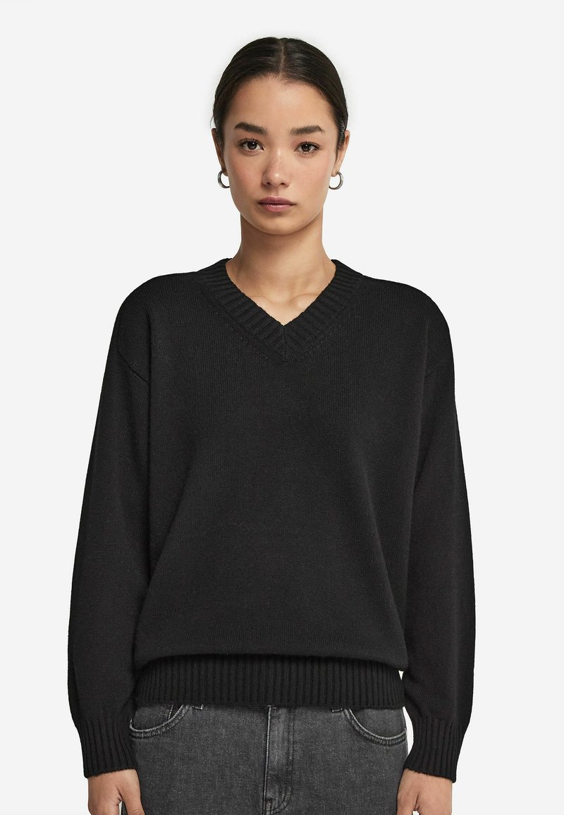 Czarny sweter dzianinowy z dekoltem w kształcie V, prążkowanym dołem i mankietami, o luźnym kroju. Miękka struktura i prosty design, idealny na co dzień.