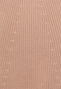 Tissu tricoté rose clair avec un motif côtelé texturé et de légères variations horizontales dans l'épaisseur du fil.