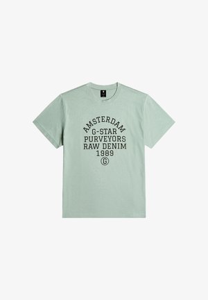 Light green cotton t-shirt featuring black text: "AMSTERDAM G-STAR PURVEYORS RAW DENIM 1989," crew neck and short sleeves, smooth texture.