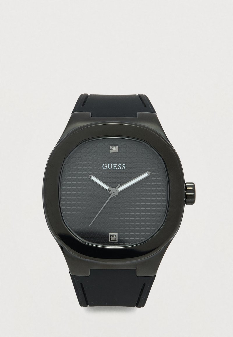 Reloj de pulsera Guess negro con esfera texturizada, manecillas plateadas, correa negra y dos pequeños marcadores cuadrados en las posiciones de las 12 y las 6 en punto.