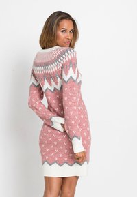 Abito maglione rosa con motivi geometrici bianchi e grigi. Presenta maniche lunghe e orlo e polsini a costine bianchi.