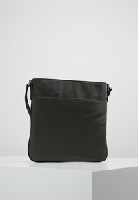 Sort syntetisk crossbody-taske med glat overflade, lynlåslukning øverst og justerbar rem. Har et enkelt, struktureret rektangulært design.