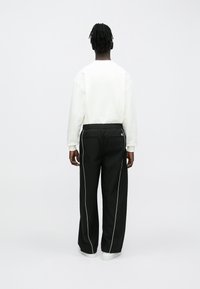 Μαύρο παντελόνι με άσπρη πλαϊνή ρίγα, ελαστική μέση και ευθεία γραμμή. Συνδυασμένο με ανοιχτόχρωμο φούτερ με στρογγυλή λαιμόκοψη.