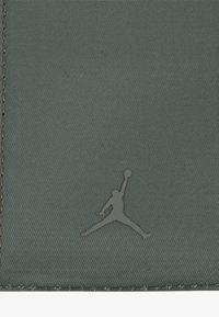 Billetera verde texturizada con un logo Jumpman gris elevado. Cuenta con material suave y bordes cosidos para mayor durabilidad.