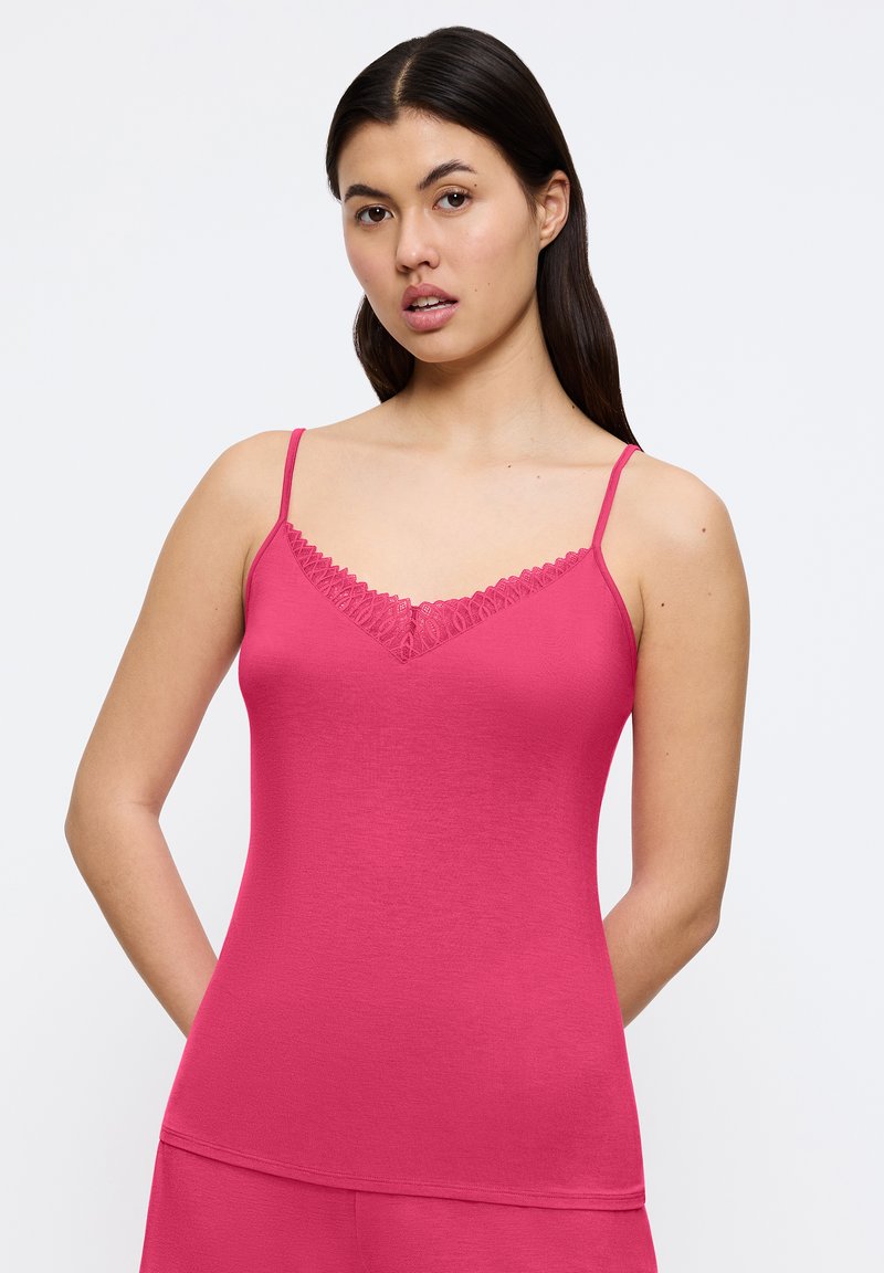 Aangesloten roze cami met dunne verstelbare bandjes en kantafwerking bij de halslijn. Zachte, elastische stof zorgt voor een gladde textuur.