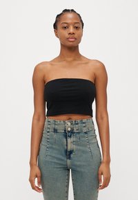 Top negru, fără bretele, din bumbac fin, asortat cu blugi din denim de un albastru deschis, cu talie înaltă, având două închideri cu nasturi.