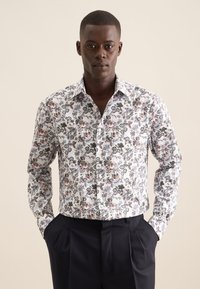 Witte button-up shirt met een kleurrijk bloempatroon in blauw, oranje en groen. Lange mouwen, slim fit ontwerp, gecombineerd met donkere broeken.