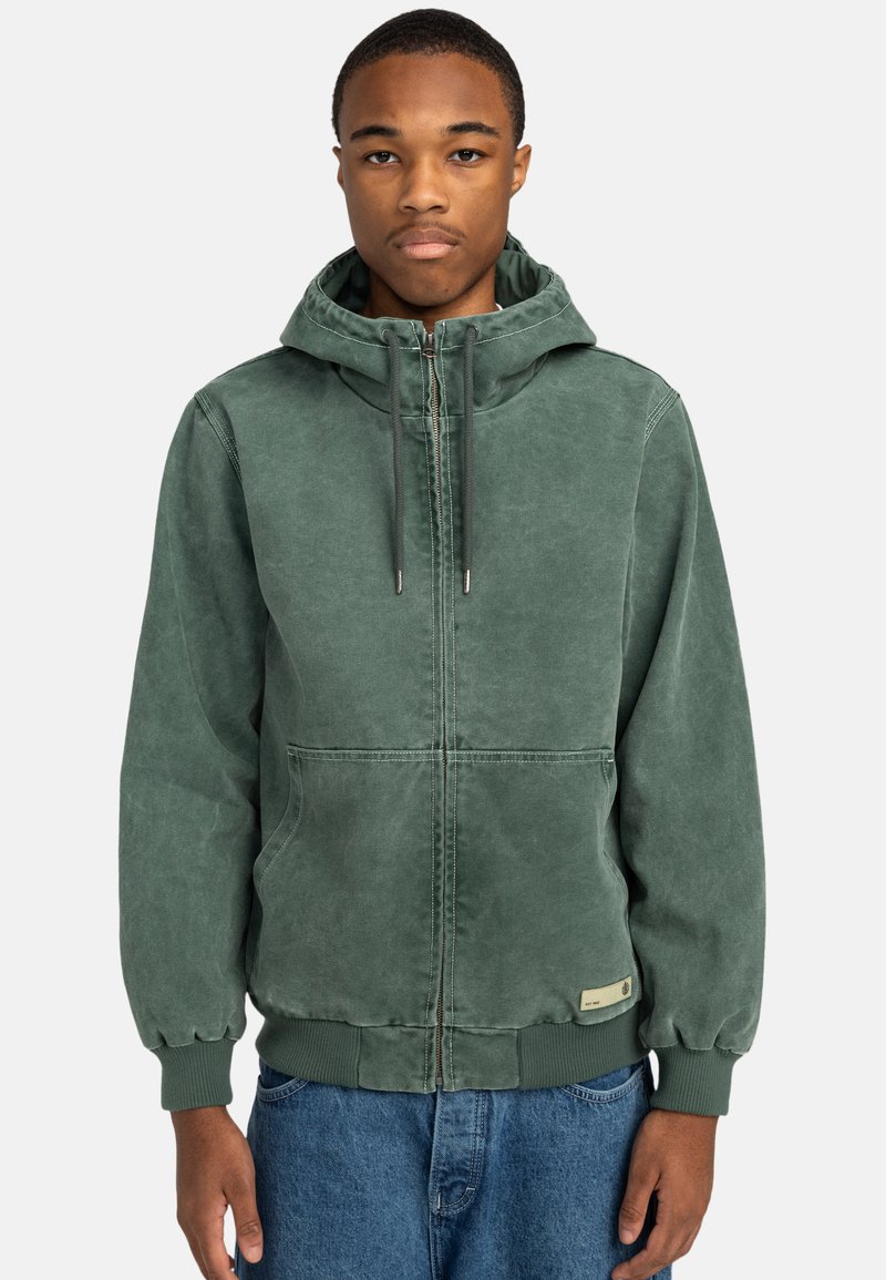 Sudadera verde con cremallera en el frente, capucha ajustable con cordón, puños y dobladillo acanalados, y dos bolsillos frontales. Tejido suave y texturizado.