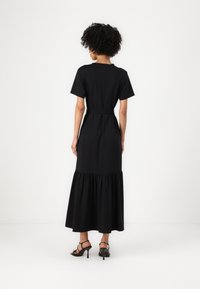 Czarna maxi sukienka z krótkimi rękawami, dopasowaną talią i rozkloszowanym, falbaniastym dołem. Gładki materiał i minimalistyczny design. Akcentowana paskiem.