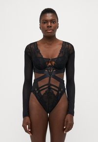 Zwarte lingerie met kant en doorschijnend materiaal, lange mouwen, een diepe halslijn en bandjes met metalen accenten op de taille.