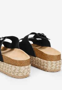 Sandali platform neri in suede con base in sughero naturale, dotati di una zeppa in corda intrecciata e un design semplice delle cinghie con un dettaglio a fibbia.