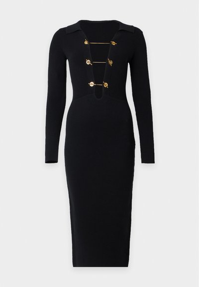 Robe midi noire côtelée à manches longues avec un profond col en V fermé par quatre fermoirs à bascule dorés horizontaux.