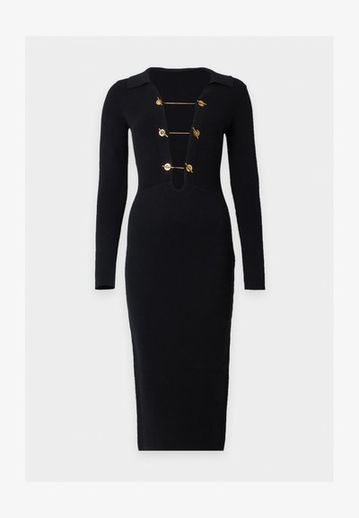 Robe midi noire côtelée à manches longues avec un profond col en V fermé par quatre fermoirs à bascule dorés horizontaux.