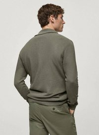 Polo grigio a maniche lunghe con maglia testurizzata, presenta un colletto classico e una vestibilità rilassata, abbinato a pantaloni verde oliva.