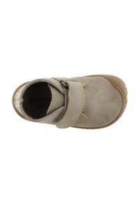 Zapato de ante gris con puntera redonda, correa de velcro y costuras amarillas. Suela de goma y marca visible en el interior.