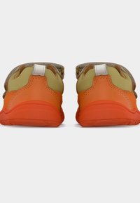 Ζευγάρι παπουτσιών χαμηλού κόστους με πορτοκαλί σόλες και πράσινο ύφασμα πάνω, εμφανιζόμενα από πίσω σε λευ κό φόντο.