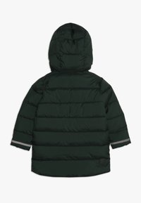 Giacca a vento verde scuro con cappuccio, caratterizzata da sezioni trapuntate orizzontali e dettagli riflettenti sulle maniche. Design semplice e funzionale.