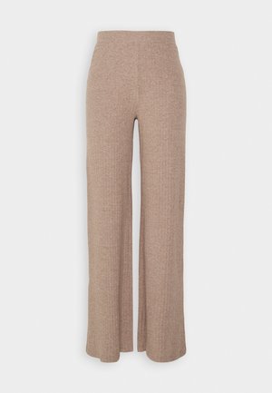 Pantalons larges en beige à côtes avec une taille haute et une texture douce, présentant une coupe loose et sans fermetures visibles.