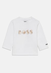 Camiseta de manga larga blanca hecha de algodón, con la palabra "BOSS" en letras multicolores en la parte frontal y el logo en la manga.