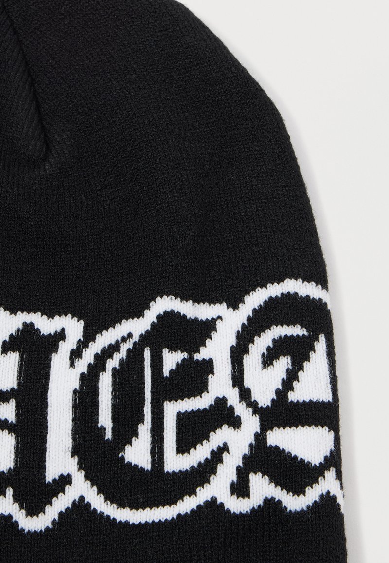 Beanie nero lavorato a maglia con un design grafico bianco caratterizzato da lettere bold e stilizzate. La texture è liscia e uniforme in tutto il suo utilizzo.