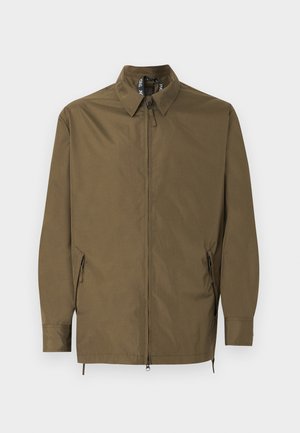 Veste marron à fermeture éclair avec col, manches longues et deux poches latérales zippées, présentée sur un fond clair uni.